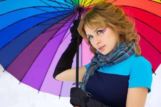 Young woman with multicolor umbrella at winter forest