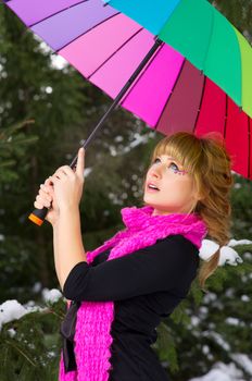Young woman with multicolor umbrella at winter forest