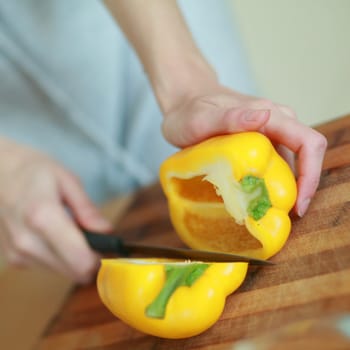 An image of hands cutting yellow paprika