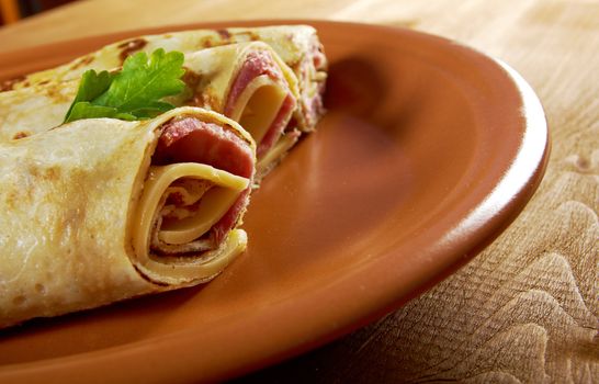 rolled pancakes stuffed ham and cheese. Shallow depth-of-field.