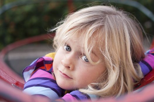 A cute girl resting on a climbing frame in a playground