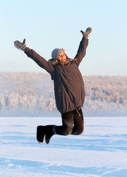 girl jumps in the snow in the sun