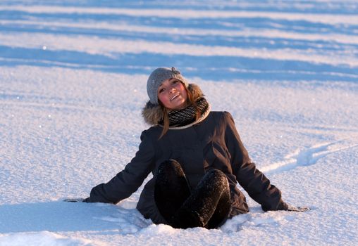 beautiful young girl sitting in the snow