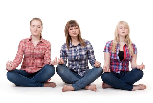 Three girls sitting in lotus posture on a white background