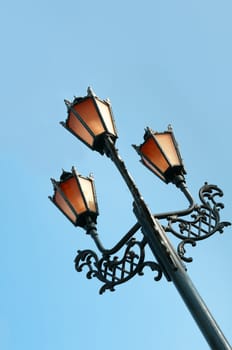 Antique metal street lamp with blue sky on background