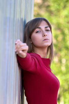 Portrait of a beautiful young girl in a red dress against the iron wall and timber