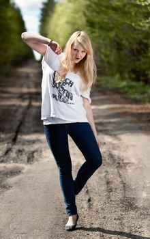 beautiful blonde in a white dress and jeans on the road in the woods