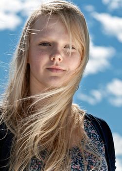 portrait of a beautiful blonde with freckles on the background of sky with clouds