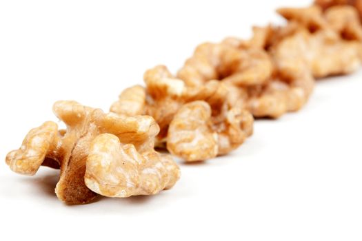 halves peeled walnuts arranged in a line on a white background