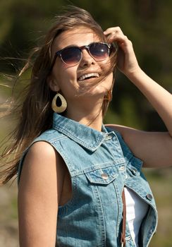 portrait of smiling girl in sunglasses and a denim vest