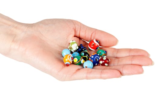 Colored glass beads in a female hand on a white background