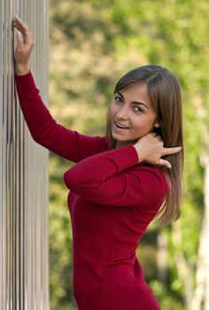 Beautiful girl in purple dress outside steel wall against the background of the forest