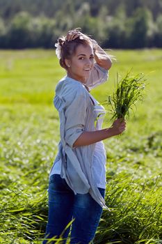 girl with a bundle of green grass in a meadow