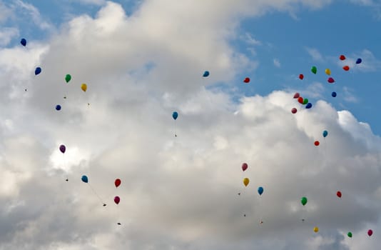 colored balloons flying in the sky with clouds