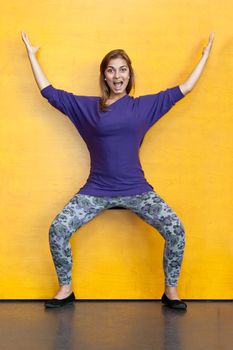 Beautiful girl in purple sweater on a background of yellow wood wall