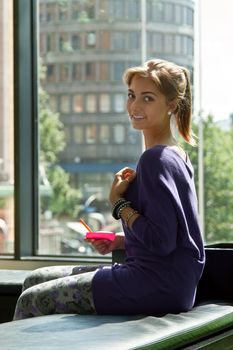 beautiful girl sitting by the window with a sticker and pen in hand