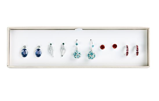 five pairs of earrings with stones in a cardboard box on a white background