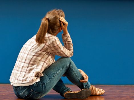 Offended by a girl sitting on the floor turned to the blue wall