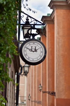 old street clock on the background of a narrow street in Stockholm, Sweden