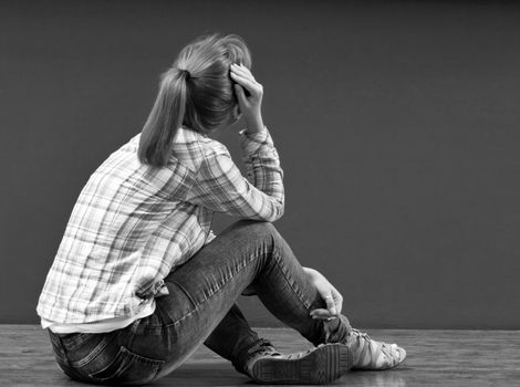 Offended by a girl sitting on the floor turned to the wall. monochrome