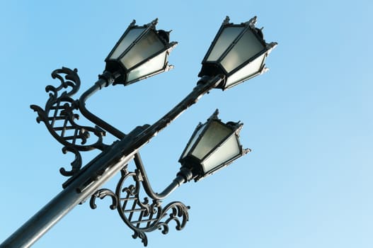 Antique metal street lamp with blue sky on background