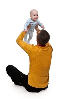 Dad is sitting on the floor and tosses baby