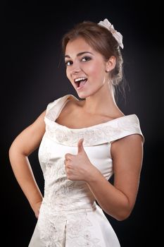 Beautiful girl in dress shows OK in the studio on a black background