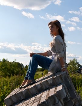 beautiful girl sitting on the ruins on the backdrop of greenery