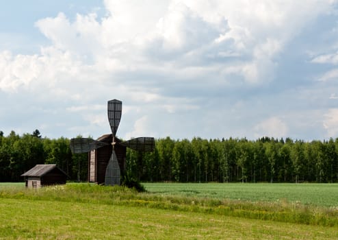 The old wooden mill on the background of forest plantations