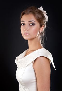 portrait of a girl in a cream dress in the studio on a black background