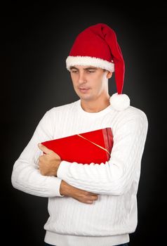 sad man in a hat Santa with a gift on a black background