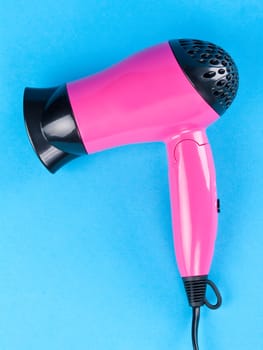 Pink hair dryer on a blue background