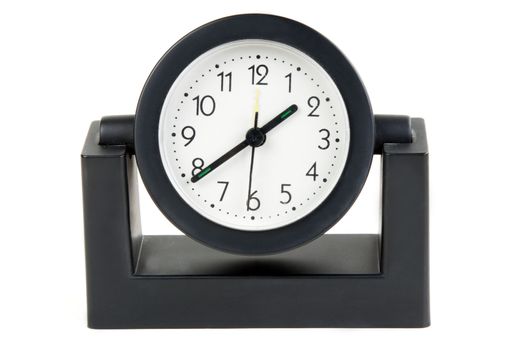 Desktops mechanical clock in a black plastic casing with a white background