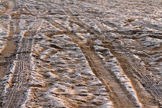 trail from the car on the frozen sand at sunset sun