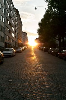 European narrow street with parked cars in the sunset light of the sun