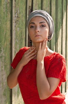 girl in the gray turban and a red sweater against a background of old shabby wooden green wall