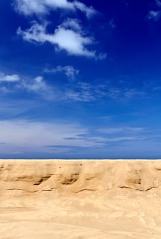 Tropical yellow sand against the blue sky with clouds