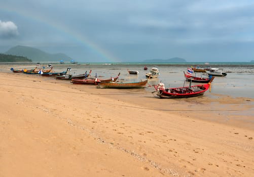 ebb of the sea a boat on the rocks in the sky with a rainbow