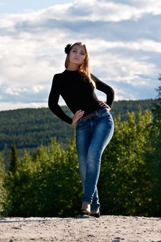 beautiful girl on a forest road in the sky with clouds