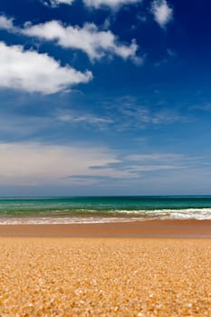 sandy beach with turquoise water and clouds in the blue sky