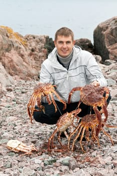 man with crabs in the Barents Sea coast, after a successful fishing