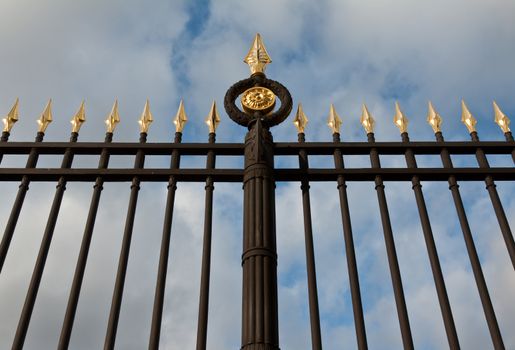 steel fence with gold spears against the sky