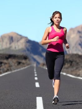 Jogging woman running. Female runner during outdoor workout in beautiful mountain nature landscape. Beautiful young mixed race fit fitness model training for marathon.