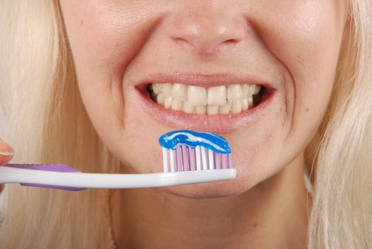 Young blonde woman brushing her teeth