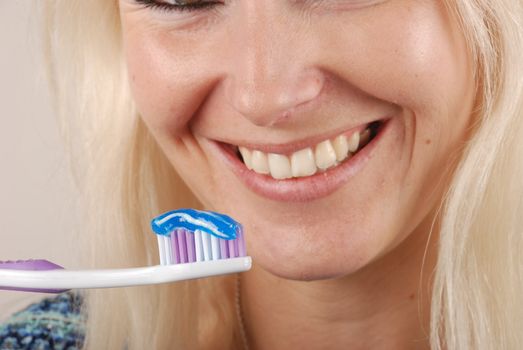 Young blonde woman brushing her teeth