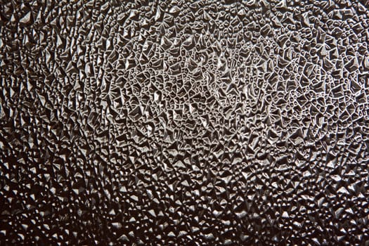 Abstract background of rippled, textured black glass with white reflections.