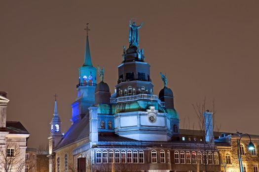 Night view of Notre Dame de Bon Secures Chapel in the Old Port section of Montreal, Quebec, Canada, 350 year old landmark built in 1771, also called The Sailor's Church, showing colorful blue lights, dome and statues on top of the church.