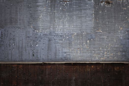 Brick wall with peeling gray paint with wooden panels underneath grunge background