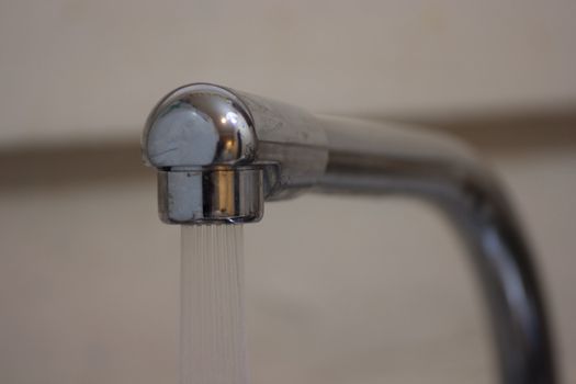 A sliver facuet with the water flowing out of the spout.