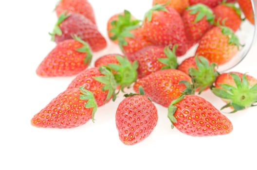 close up red ripe  strawberry spilling out of glass over  white background
